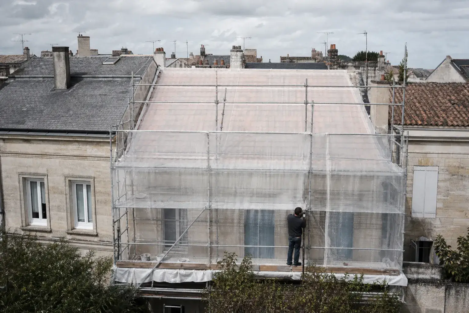 Toiture entière d’une petite maison de ville, échafaudée et bâchée du faîtage jusqu’à l’égout