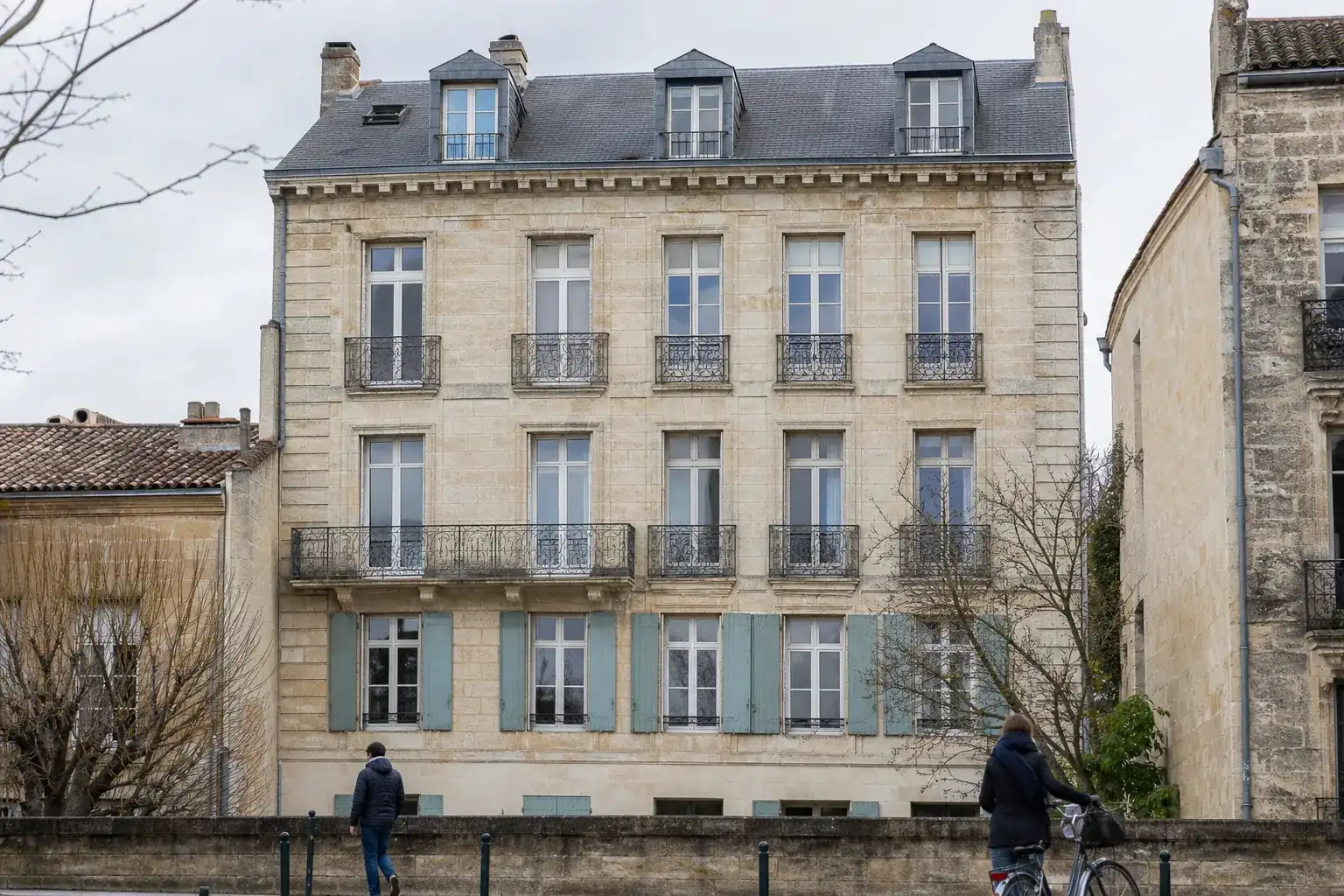 Immeuble bordelais du XVIIIe siècle en pierre de taille, balcons en fer forgé et toiture en ardoise à lucarnes